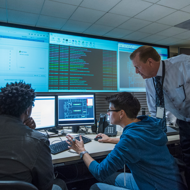 Office scene with IT professionals monitoring data across multiple screens, highlighting infrastructure risks and disaster recovery challenges.