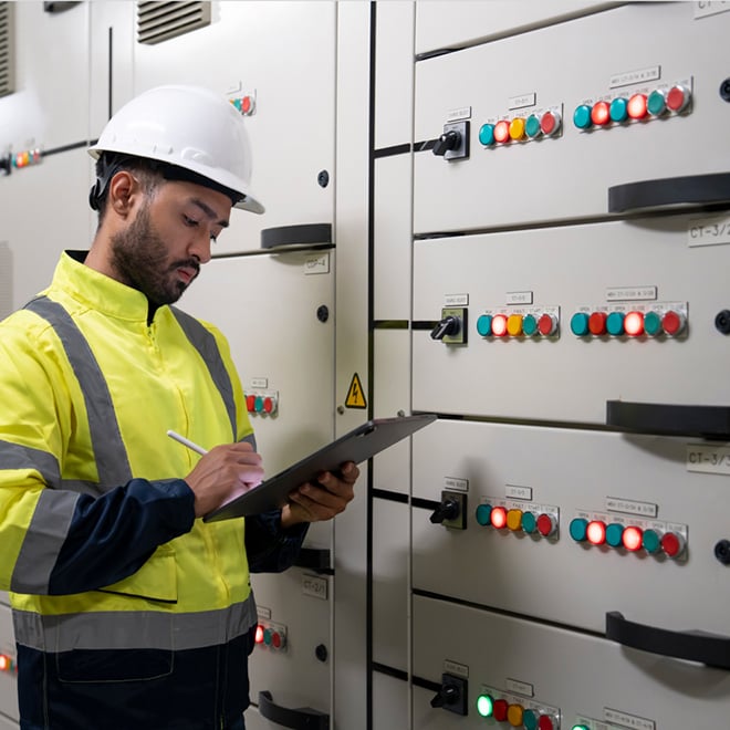 Engineer inspecting an electrical panel, symbolizing the rising power demands and infrastructure challenges of scaling AI and high-density workloads.