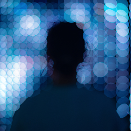 Silhouette of a person with blue bokeh lights, representing the scale and complexity of high-density workloads like AI and big data.